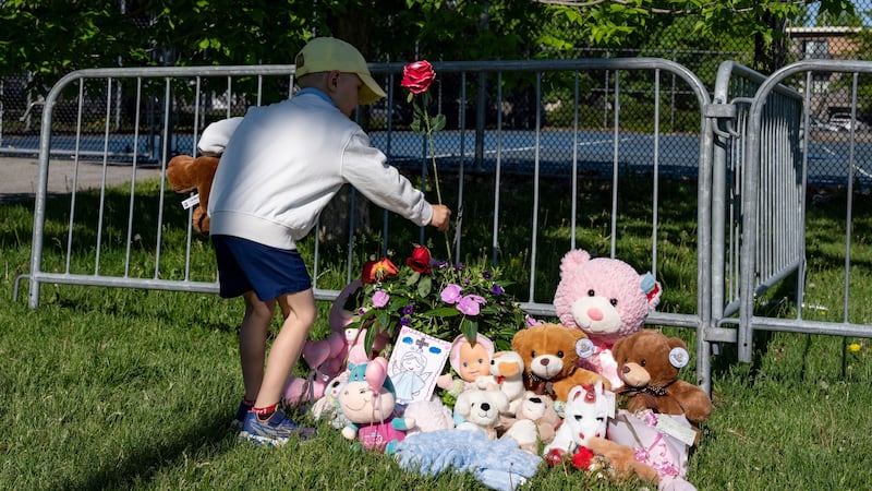 Un niño coloca flores en un altar improvisado en el Parc Ouellette, después de que una niña...