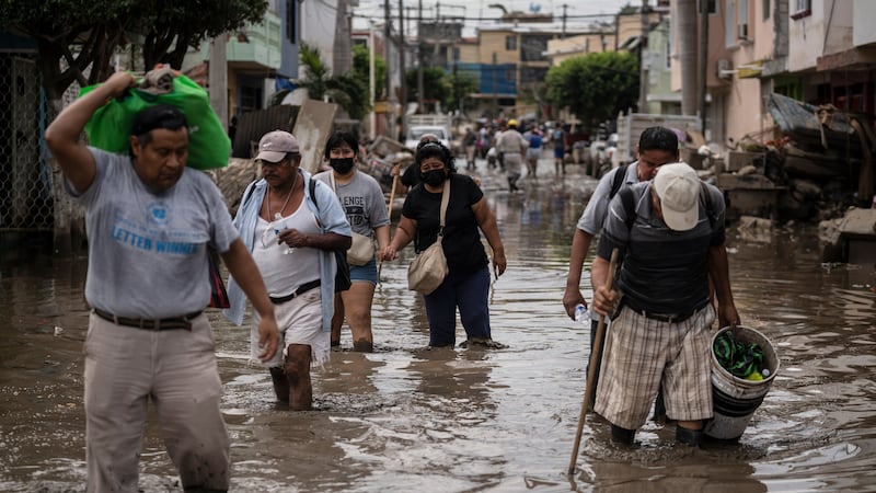ARCHIVO - Personas caminan por una calle inundada en Poza Rica, en el estado de Veracruz,...