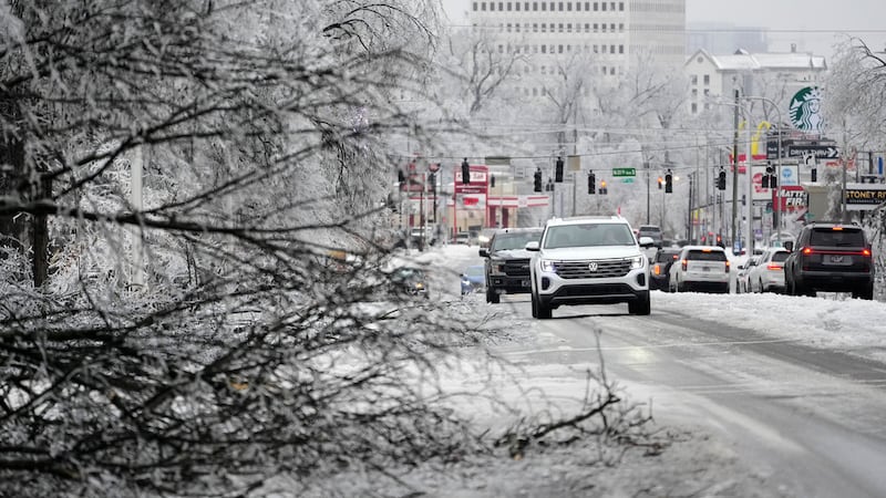 Un conductor pasa junto a una rama llena de hielo por la avenida West End durante una tormenta...