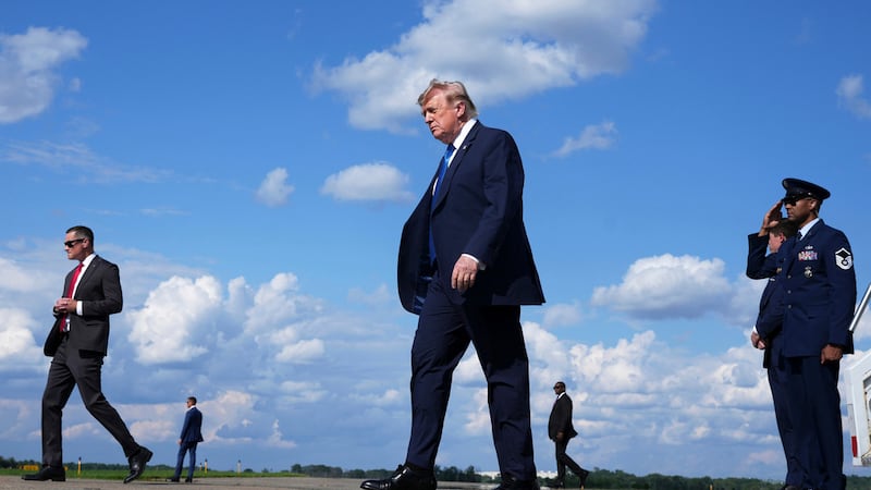 El presidente Donald Trump, en el centro, baja del Air Force One en el Aeropuerto Municipal de...