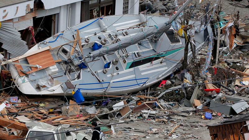 ARCHIVO-Un hombre pasa junto a un yate varado en una zona azotada por un tsunami en Ofunato,...